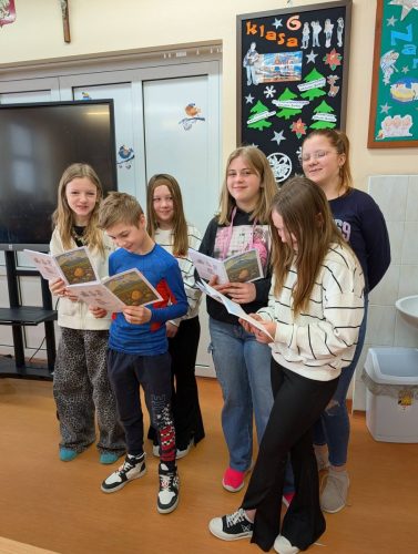 Dzieci w bibliotece wypożyczają książeczkę "Jak to z Grulkiem było"