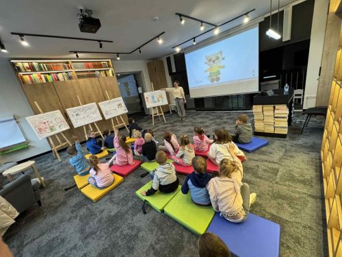 Dzieci na zajęciach w bibliotece rysują, bawią się.