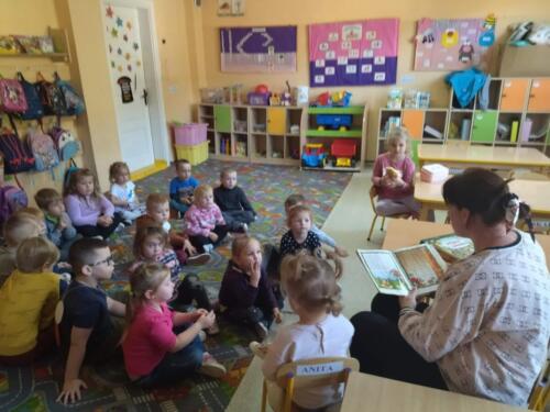 Przedszkolaki słuchają jak zaproszona mama czyta książkę