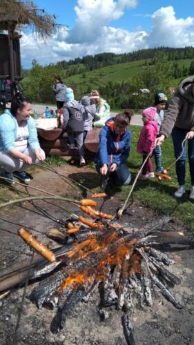 Piknik na szczycie Łapszanki. Dzieci bawią się na łące, pieką kiełbaski i śpiewają piosenki przy akompaniamencie gitary