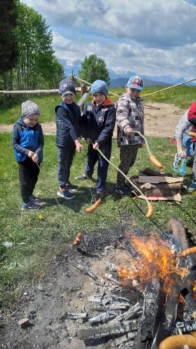 Piknik na szczycie Łapszanki. Dzieci bawią się na łące, pieką kiełbaski i śpiewają piosenki przy akompaniamencie gitary